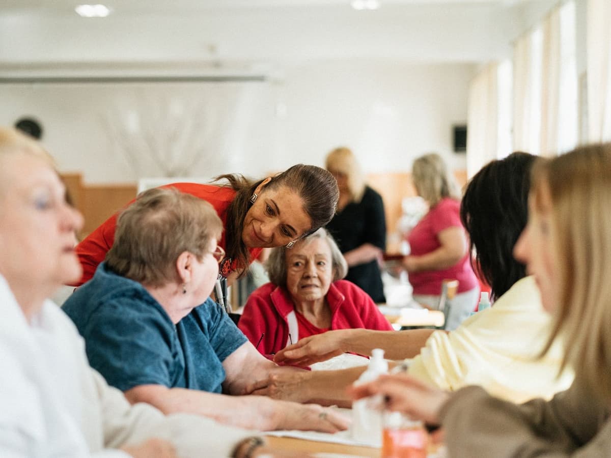 Begeleider in gesprek met senioren aan tafel in een buurtcentrum